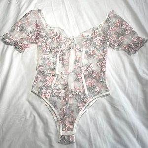 Transparent body suit with pink and silver floral embroidery.